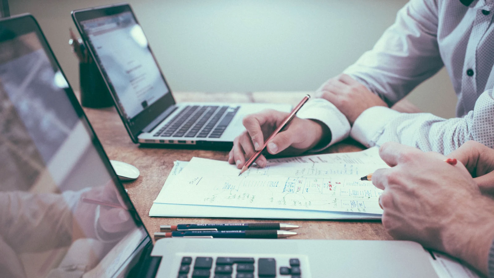 Profesionales trabajando en una mesa con computadoras y documentación